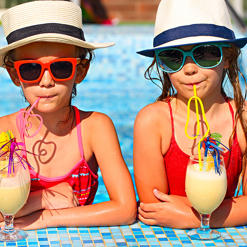 Zwei kleine Mädchen trinken Cocktails im Pool